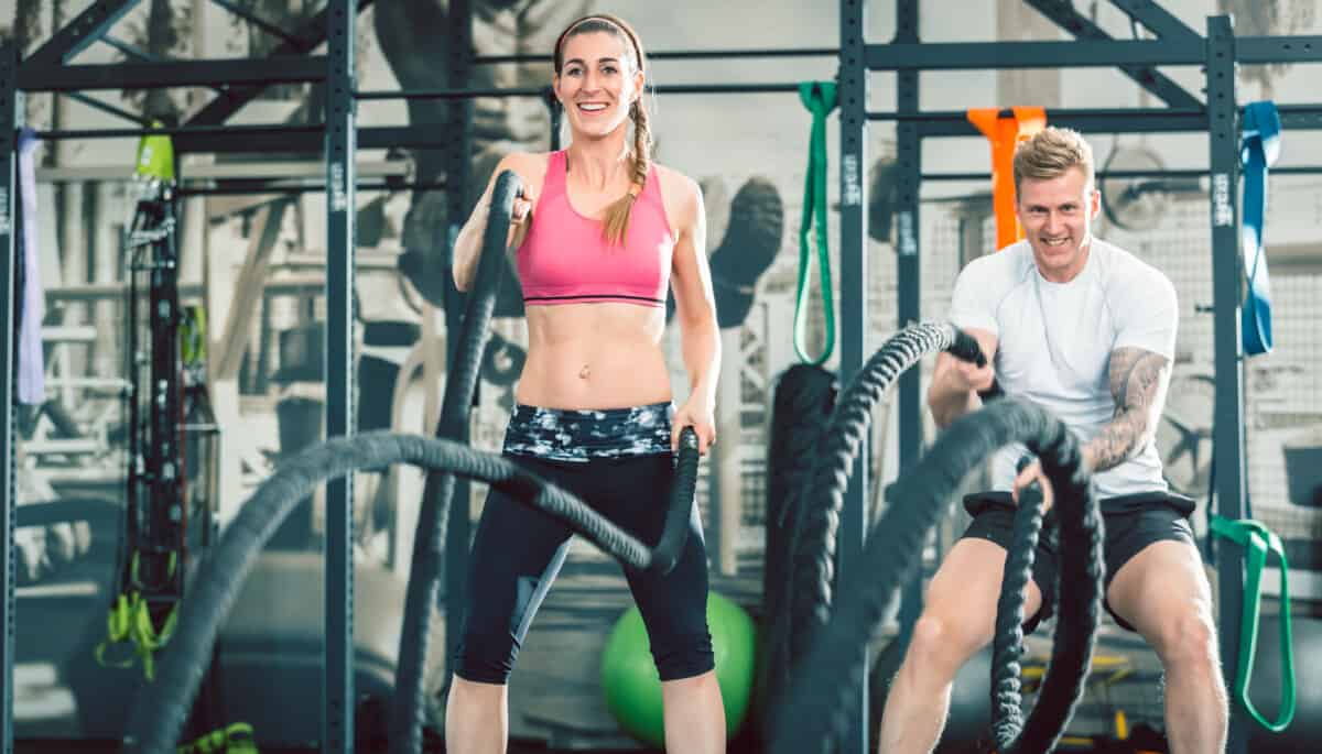 fit man and woman exercising with battling ropes how to lose 30 pounds in 3 months exercise hiit workouts