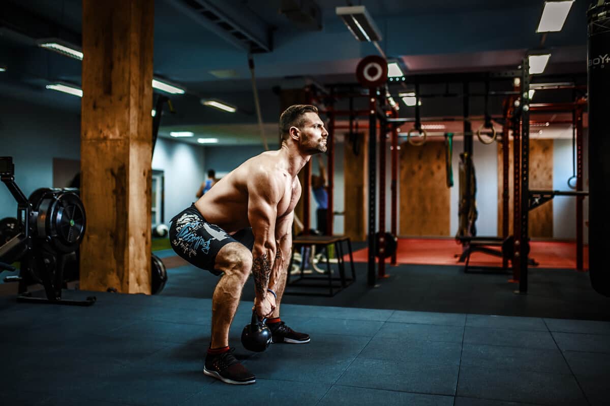 fit man lifting kettlebell for intense intense exercise for love handles