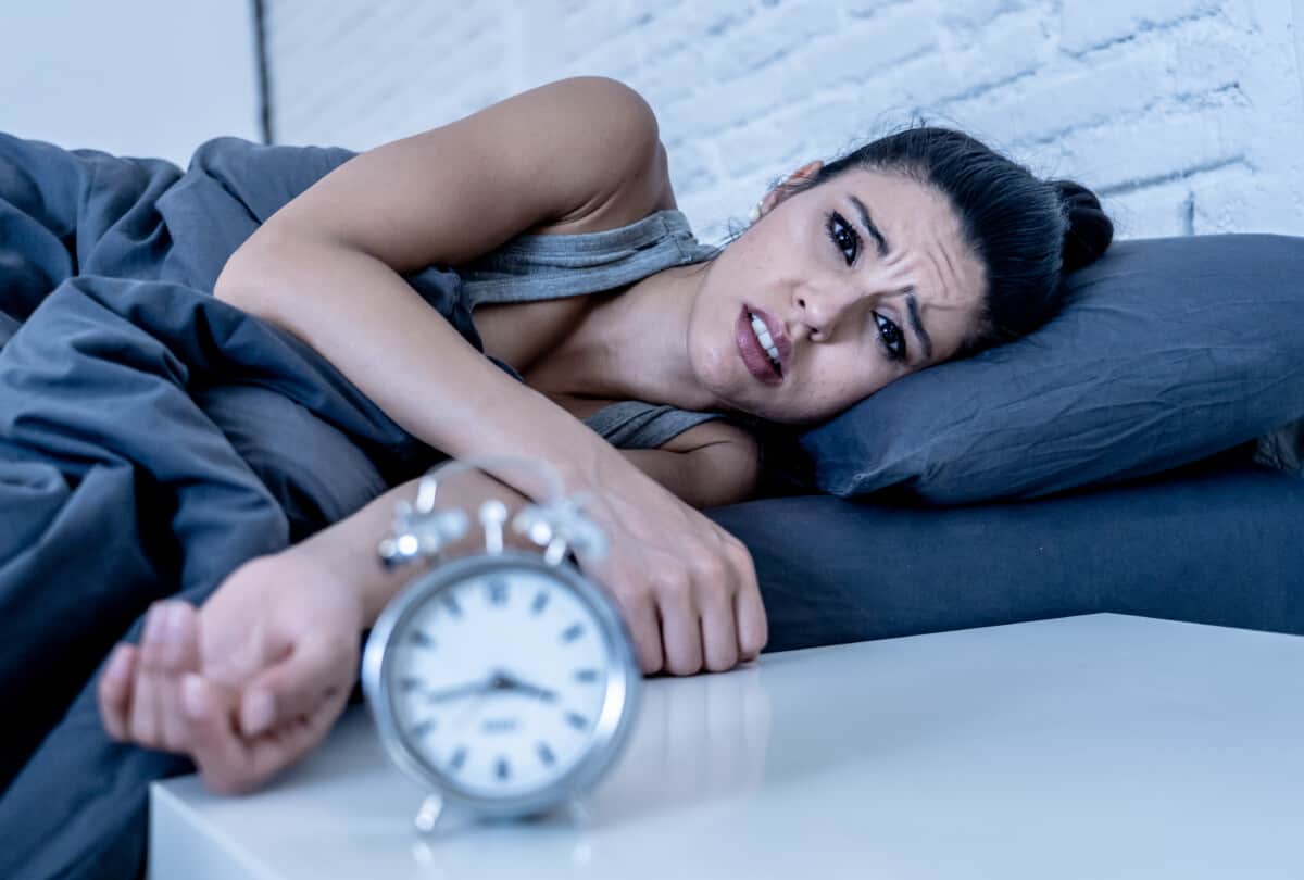 attractive woman staring at alarm clock trying to sleep feeling stressed depressed and sleepless