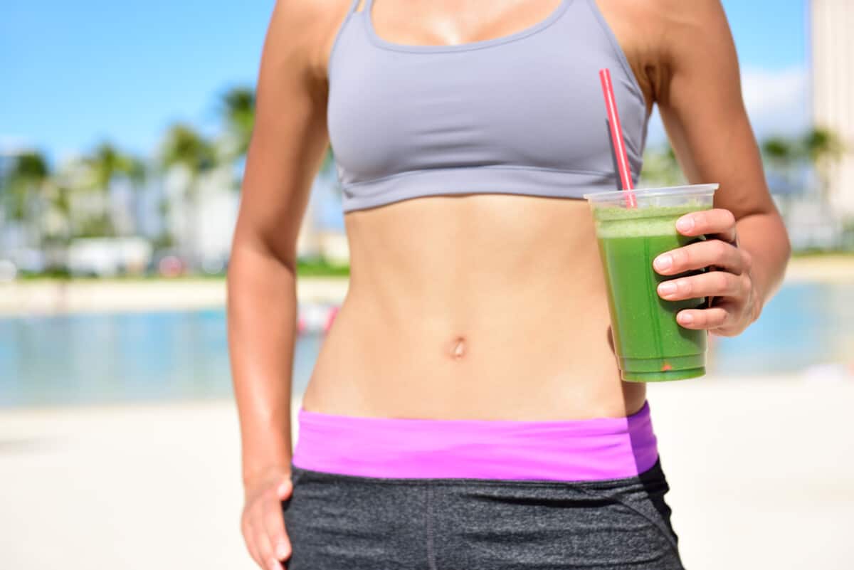 woman drinking greens powder on beach