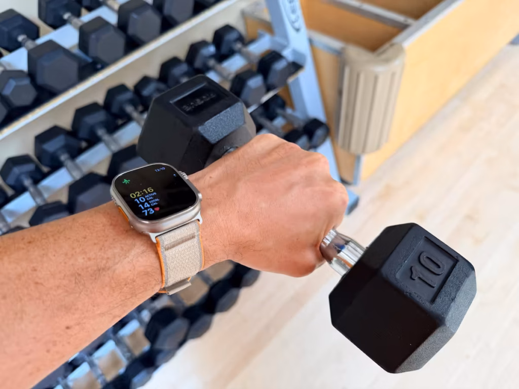 apple watch ultra 4 dumbbell strength training Trainer Josh is gripping a dumbbell while wearing an Apple Watch Ultra 4 displaying strength-training workout metrics.