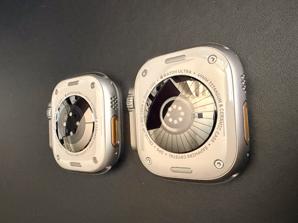 apple watch ultra4 vs ultra2 rear sensor layout Rear view of Apple Watch Ultra 2 on the left and Ultra 4 on the right, showing different circular sensor-window arrangements.